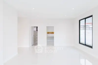 Spacious minimalist living room with large window and glossy white floors