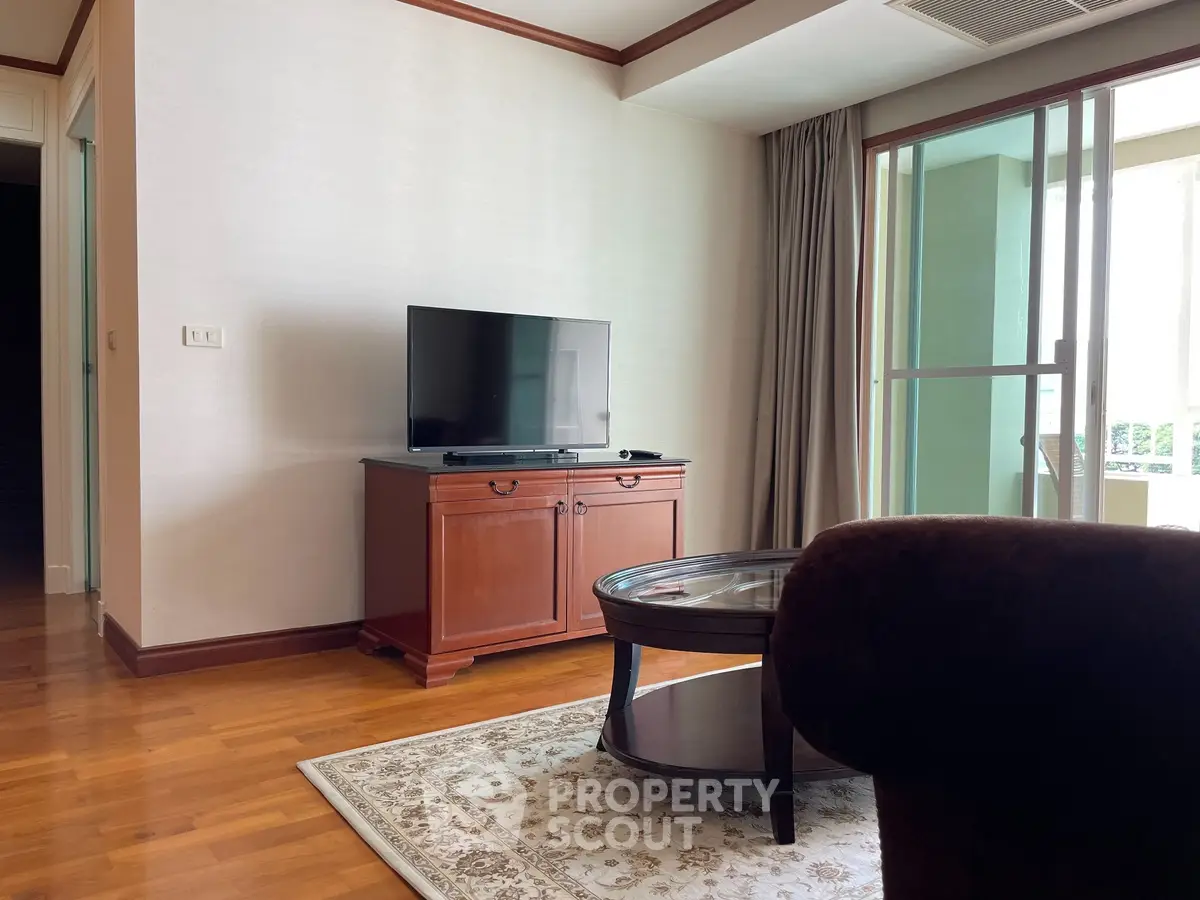 Spacious living room with elegant wooden furniture and large window for natural light.