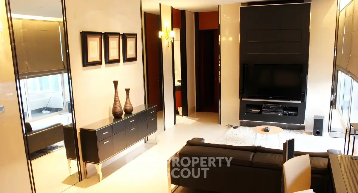 Luxurious modern living room with sleek black furniture and large TV setup.