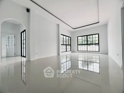 Spacious modern living room with large windows and glossy floors.