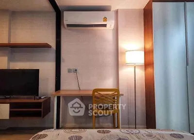Modern bedroom with stylish desk, TV, and air conditioning unit.