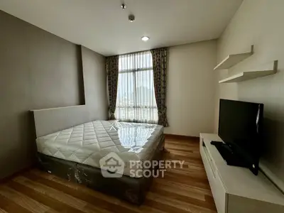 Modern bedroom with large window and TV, featuring stylish wooden flooring and elegant curtains.