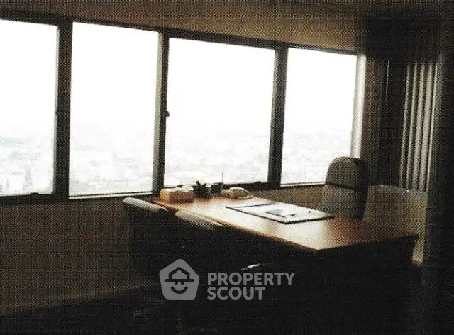Spacious office with large windows offering panoramic city views, ideal for professional work environment.