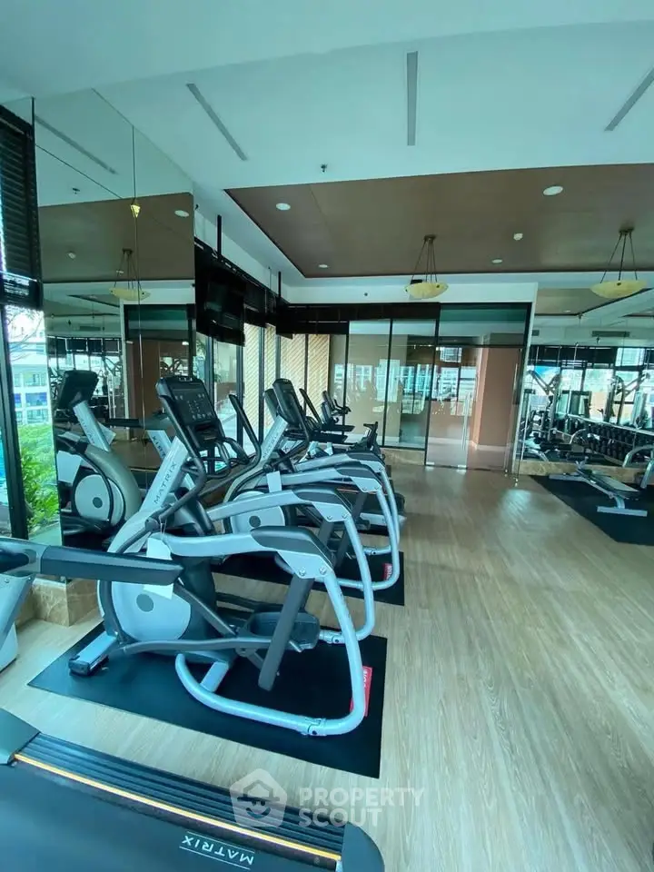 Modern gym with state-of-the-art equipment and mirrored walls in a luxury residential building.