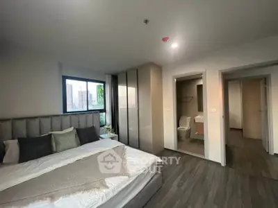 Modern bedroom with ensuite bathroom and large window offering natural light.
