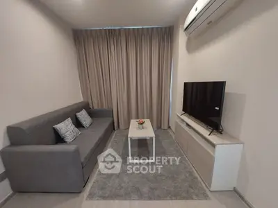 Modern living room with gray sofa, TV, and air conditioning unit.