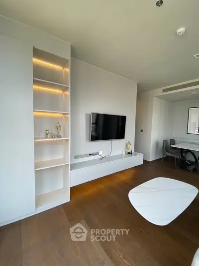 Modern living room with sleek TV setup and elegant dining area, featuring wooden flooring and ambient lighting.