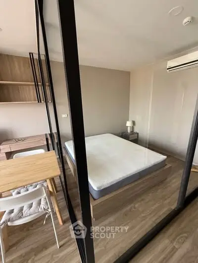 Modern bedroom with glass partition, wooden flooring, and air conditioning in a stylish apartment.