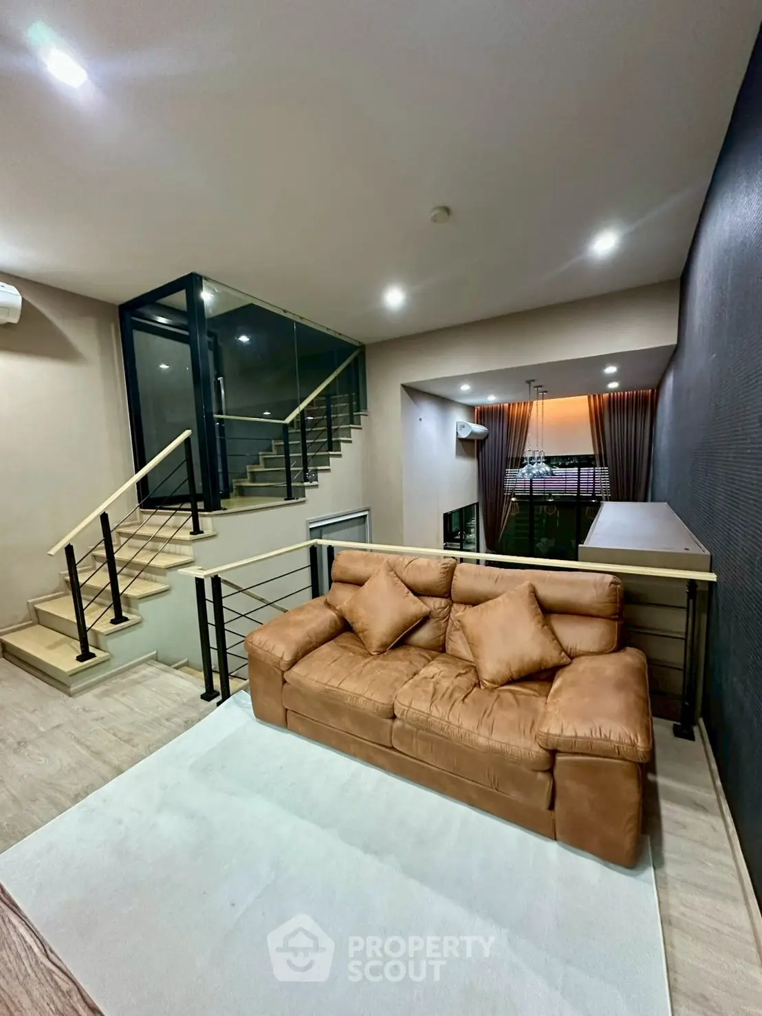 Modern living room with leather sofa and staircase in stylish duplex apartment