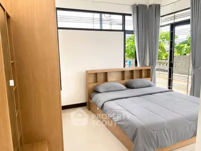 Spacious bedroom with modern design and large windows offering natural light and garden view.
