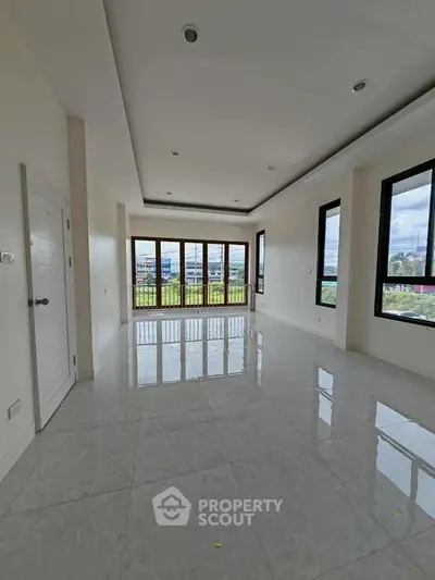 Spacious living room with large windows offering a panoramic view, high ceilings, and glossy tiled floors.