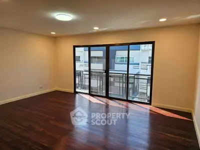 Spacious living room with large windows and hardwood floors in modern apartment.