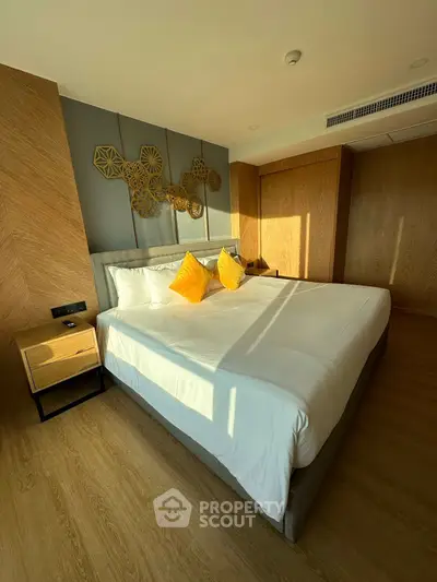 Modern bedroom with stylish decor and natural light, featuring a comfortable bed and wooden accents.