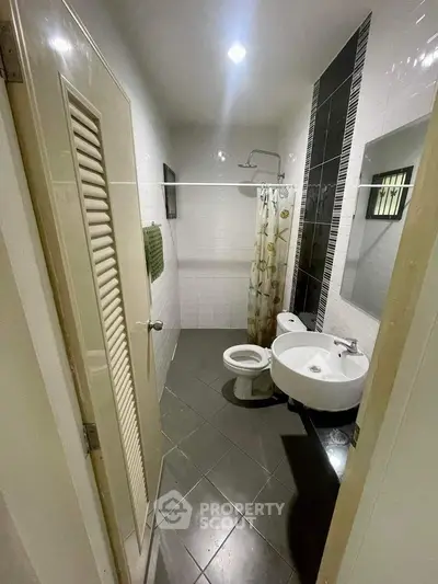 Compact and functional bathroom with white fixtures, tiled flooring, and a shower area, ideal for urban living spaces.