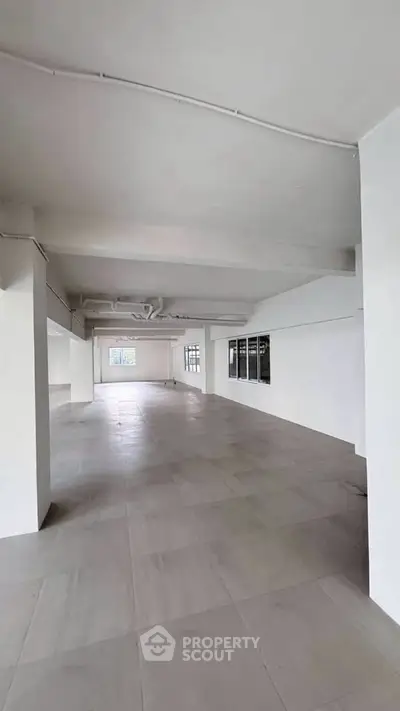 Spacious open-plan interior with large windows and modern flooring, ideal for versatile use.