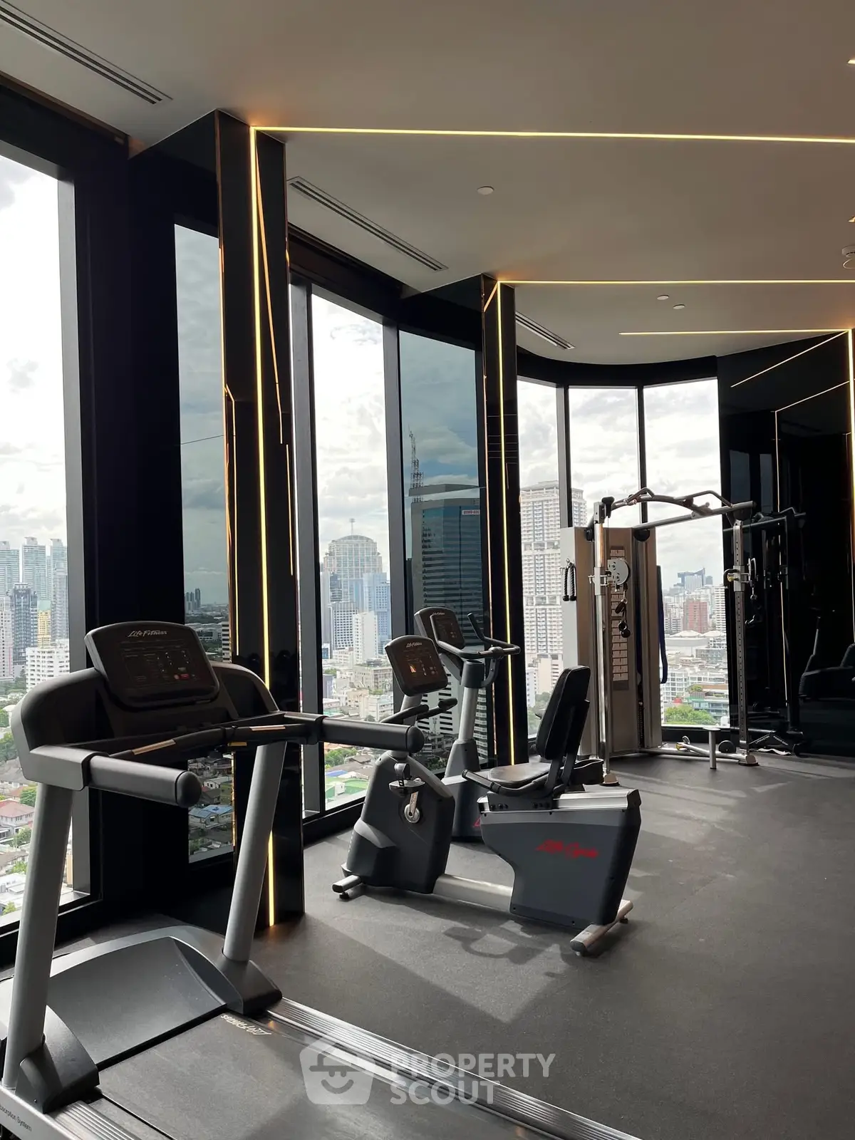 Luxurious high-rise gym with panoramic city views and modern fitness equipment.