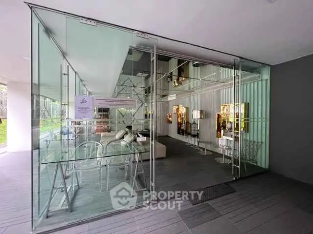 Modern glass-walled entrance to a stylish building with sleek interior design.