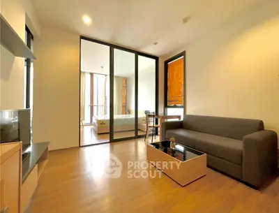 Modern living room with wooden flooring and glass partition leading to bedroom