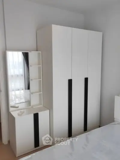 Modern bedroom with sleek white wardrobe and matching dresser with mirror.