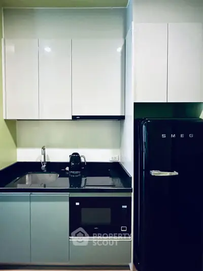 Modern kitchen with sleek cabinets, black countertop, and retro-style SMEG fridge.
