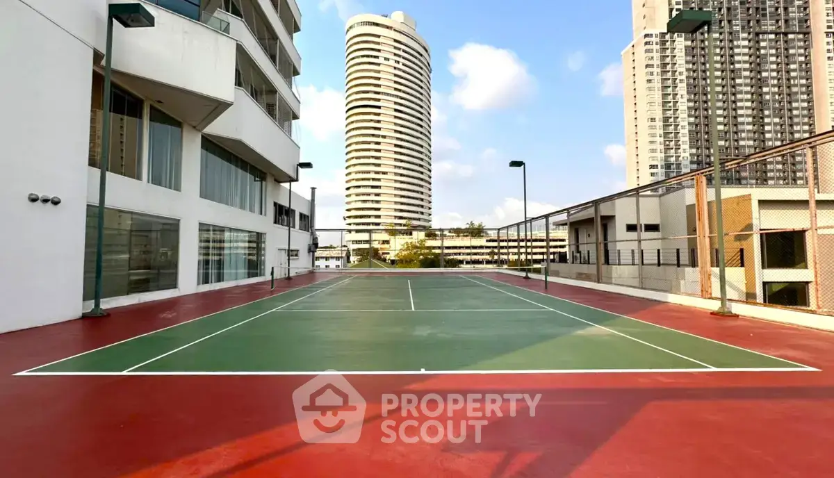 Modern apartment complex with tennis court and city skyline view