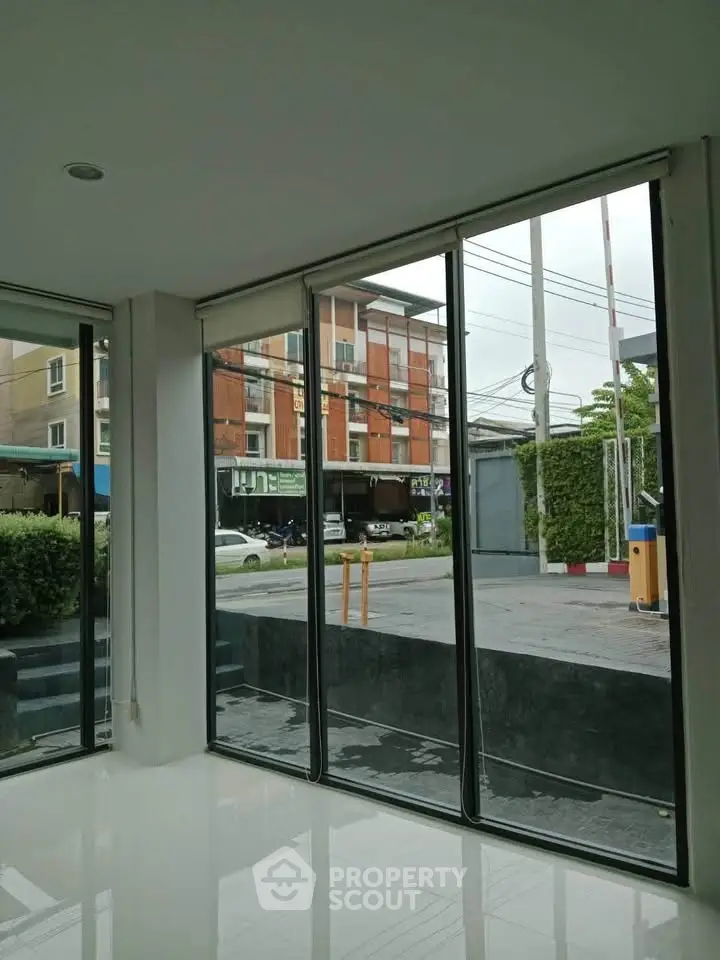 Spacious modern interior with large windows offering urban street view, perfect for natural light lovers.