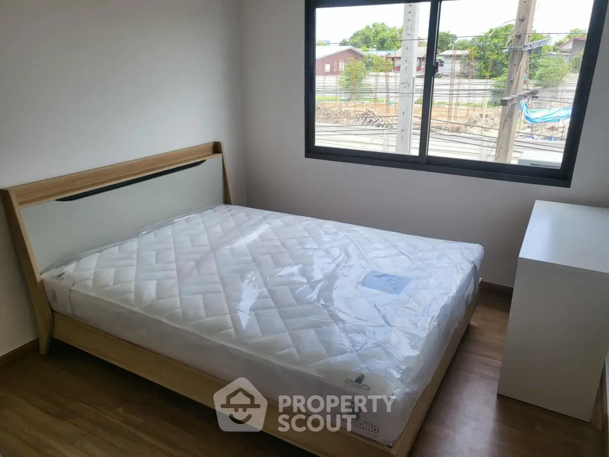 Modern bedroom with large window and new mattress in minimalist design.