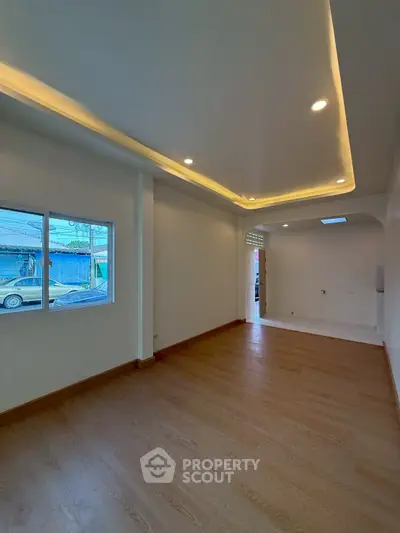 Spacious empty room with wooden flooring and recessed lighting