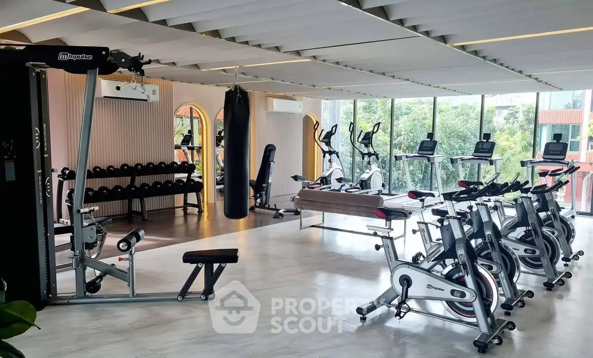 Spacious modern gym with state-of-the-art equipment and large windows offering scenic views.