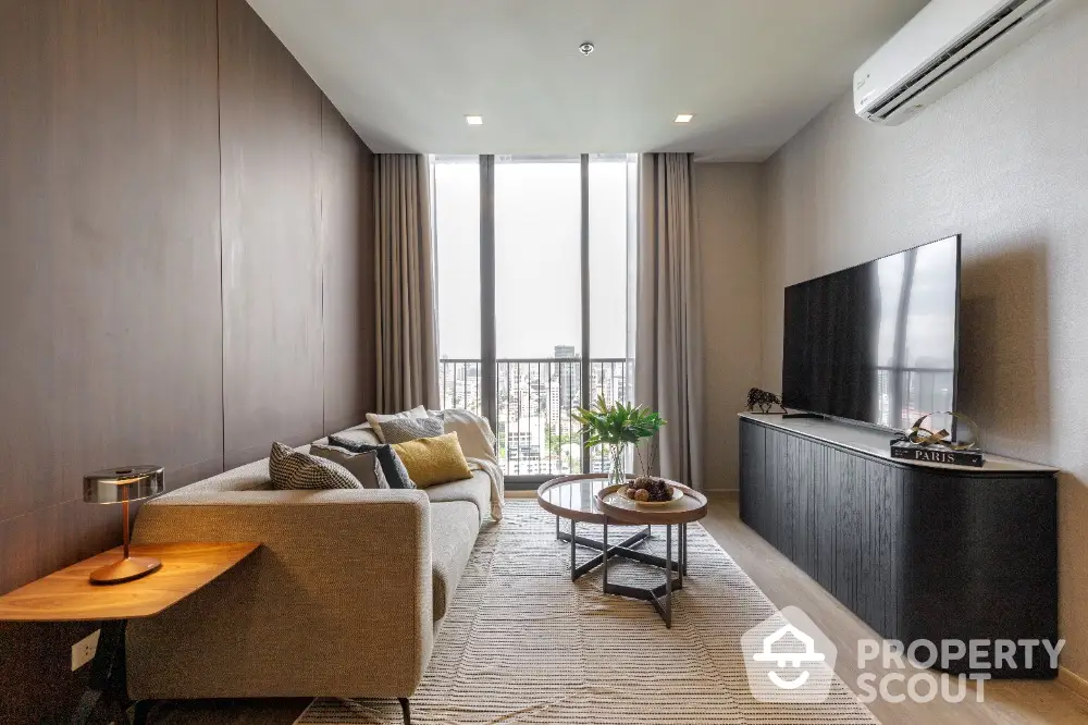 Modern living room with large windows and stylish decor in a high-rise apartment.