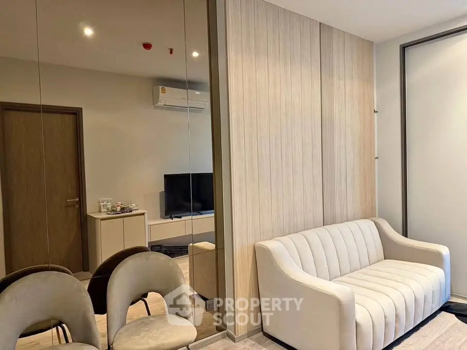 Modern living room with elegant sofa and mirrored wall, featuring a sleek air conditioning unit and stylish decor.