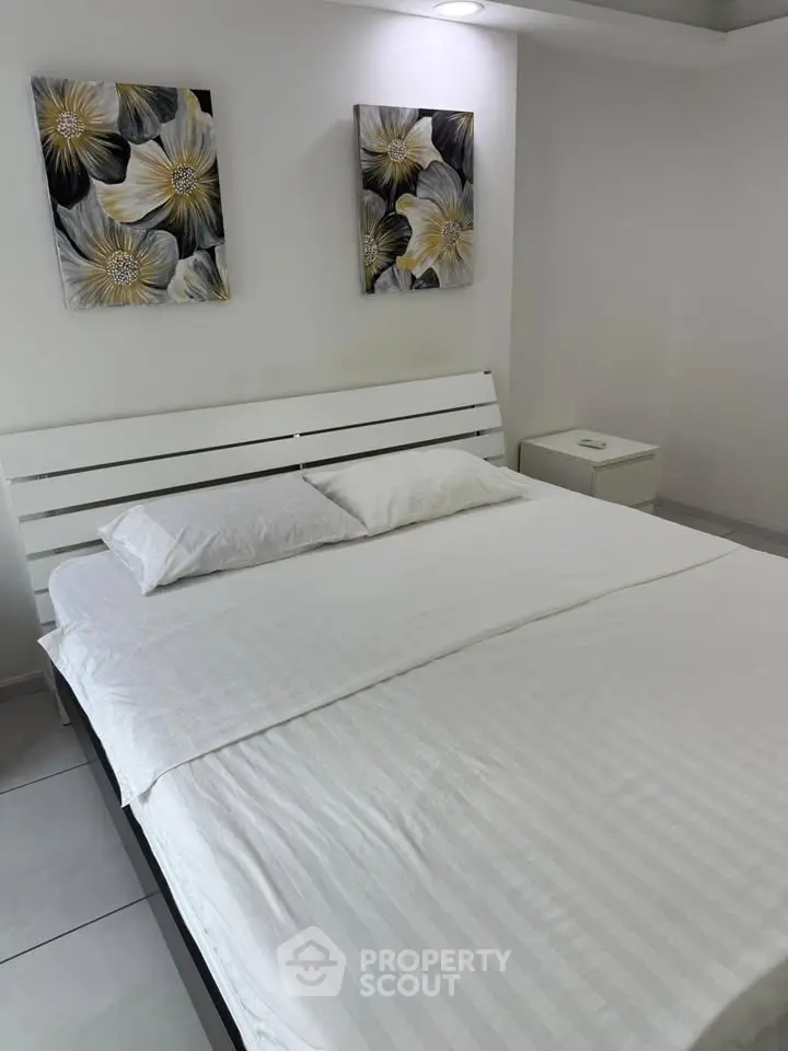 Modern bedroom with white bed and floral artwork, perfect for a serene living experience.