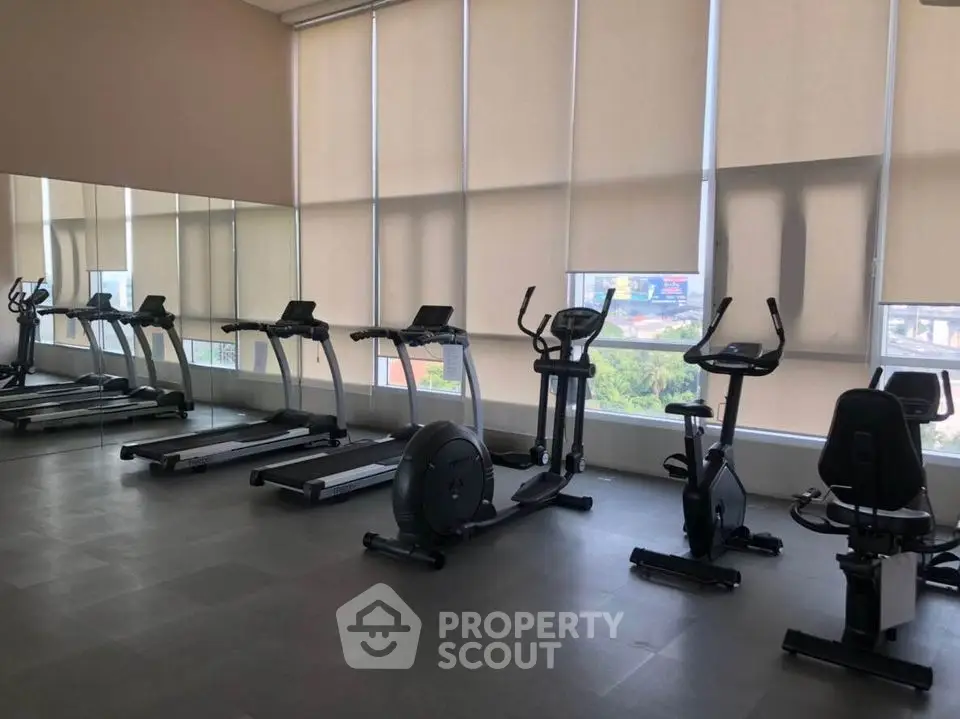 Modern gym with exercise equipment and large windows in upscale residential building.