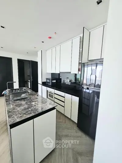 Modern kitchen with sleek black and white cabinetry and marble island