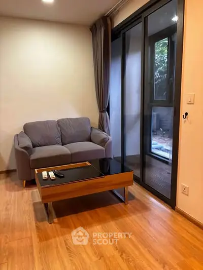 Cozy living room with modern sofa and glass coffee table, featuring large sliding doors to a private balcony.