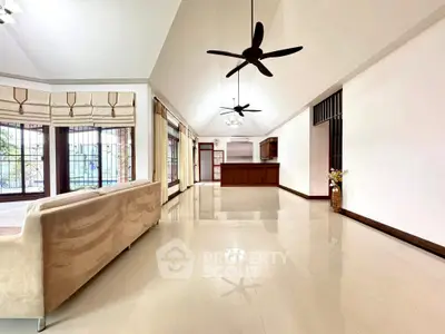 Spacious open-plan living room with modern ceiling fans and large windows.