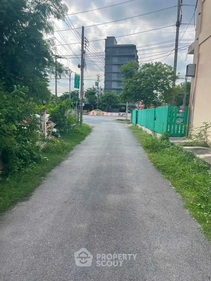 Scenic pathway leading to modern building with lush greenery and clear sky.