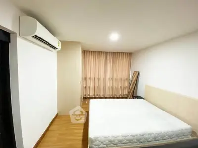 Spacious bedroom with modern air conditioning and natural light from large windows.