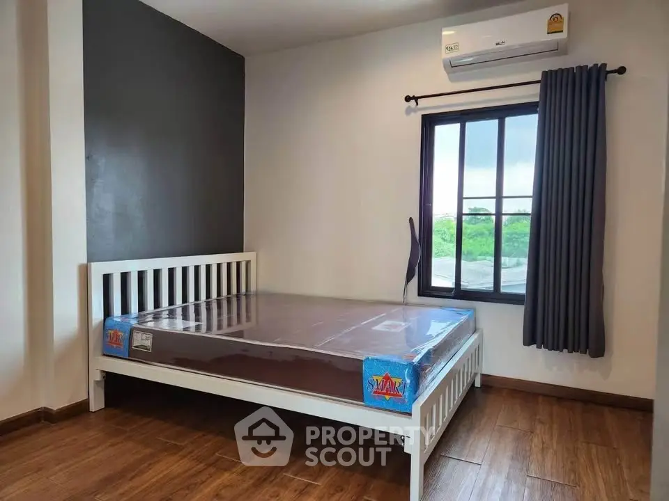 Modern bedroom with wooden flooring and large window view.