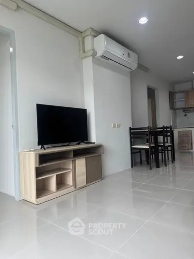 Modern living room with sleek TV stand and dining area in open layout apartment.