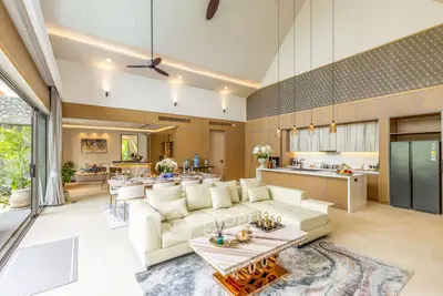 Luxurious open-plan living room with high ceilings and modern kitchen in a tropical villa.