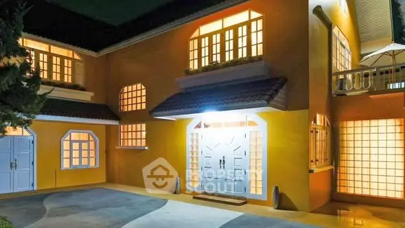 Charming yellow house with bright windows and elegant entrance at night.