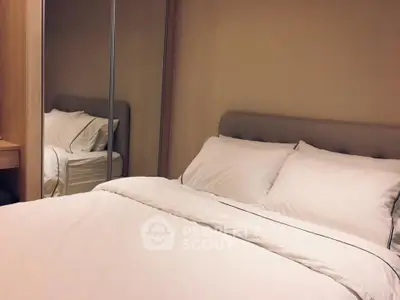 Cozy bedroom with plush bedding and mirrored wardrobe in modern apartment.