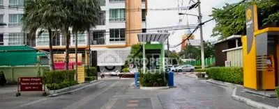 Modern apartment building entrance with security gate and lush greenery.