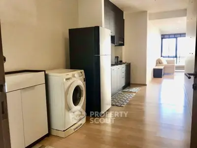 Modern apartment with sleek kitchen and washing machine, featuring bright natural light and cozy living area.