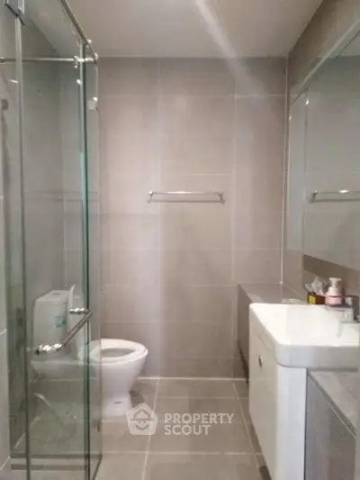 Modern bathroom with glass shower and sleek fixtures in contemporary apartment.