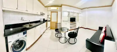 Modern open-layout kitchen and living area with sleek black and white design, featuring built-in appliances.