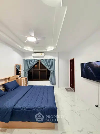 Spacious modern bedroom with elegant blue decor and large window view.