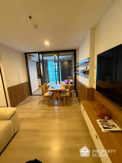 Modern living room with dining area and large TV, featuring wooden flooring and stylish decor.