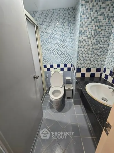 Modern bathroom with mosaic tiles and built-in bathtub in a stylish apartment.